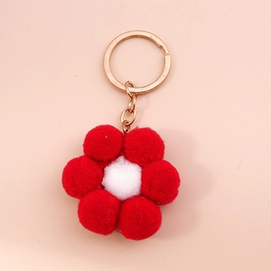 Detailed macro view of a red and white plush pom-pom flower keychain with a gold ring