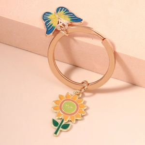 Detail of rose gold keychain with enamel sunflower and blue gradient butterfly charms