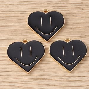 Detail of heart-shaped black enamel smiley face charms with golden alloy base for DIY