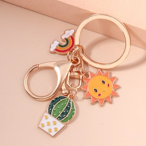 Detail of cartoon enamel keychain with sun, cactus and rainbow charms in gold finish