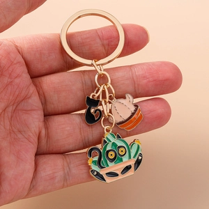 Detailed close-up of a golden alloy keychain with enamel cat and cactus charms