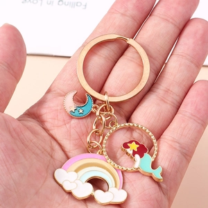 Dettaglio di ciondoli a sirena e arcobaleno su un portachiavi in metallo dorato lucido