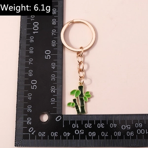 Vue détaillée d'un porte-clés bambou vert de 95 mm mesuré avec une règle sur fond rose