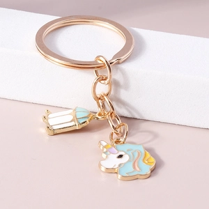 Porte-clés licorne dorée avec pendentifs émaillés colorés sur un socle blanc épuré