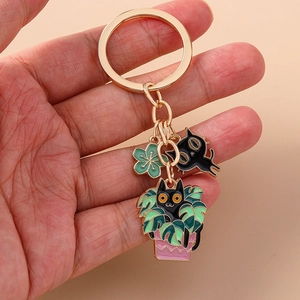 Detailed look at gold enamel keychain featuring cartoon black cats and monstera charms
