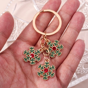 Porte-clés de Noël en flocon doré avec émail vert et strass rouges tenu à la main