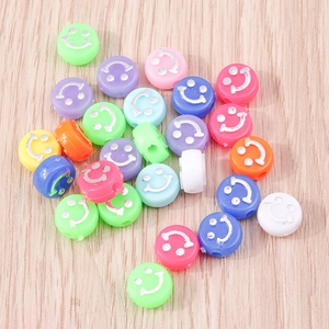 Dettaglio di perline colorate in acrilico con faccine sorridenti su legno per gioielli DIY