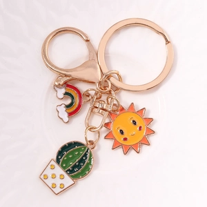 Detail of sunflower and rainbow enamel charms on a golden keychain over white ceramic