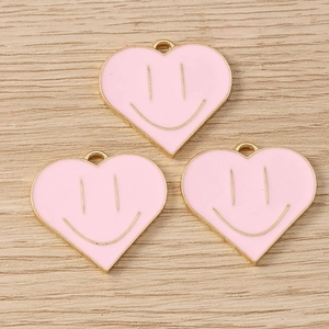 Detailed view of pink heart-shaped smiley charms with gold metal edges for DIY jewelry