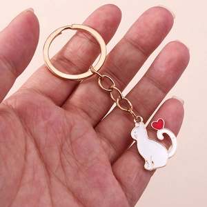 Gros plan d'un porte-clés doré avec pendentif chat blanc et petit cœur rouge mignon