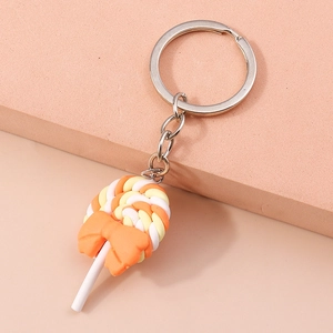 Detailed close-up of a lollipop keychain with orange and white spiral patterns and bow