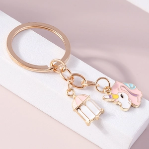 Détail d'un porte-clés licorne doré avec breloques lanterne en émail rose poli