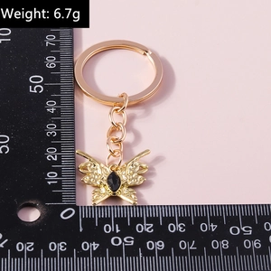 Detailed view of butterfly keychain with black gemstone weighing 6.7g on scale