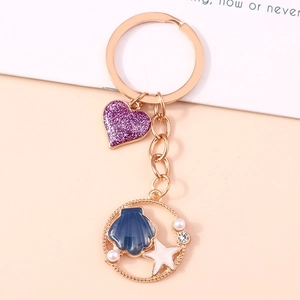 Portachiavi con stella marina, conchiglia, cuore glitterato viola e perle per zaini