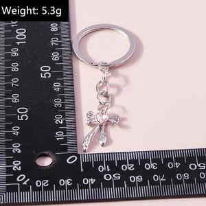 Silver bow keychain with pink heart gemstone and scale showing 5.3g weight
