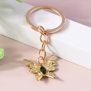 Golden baroque butterfly keychain with black gemstone on a white marble display
