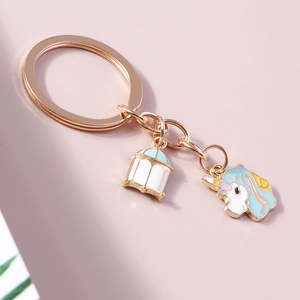 Détail d'un porte-clés doré avec breloques en émail de licorne et de cage à oiseaux
