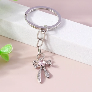 Creative silver metal bow keychain with a pink heart gemstone and textured engraving detail