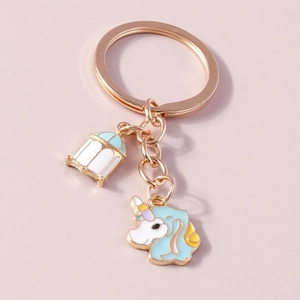 Détail d'un porte-clés licorne doré avec breloque lanterne bleue sur fond rose