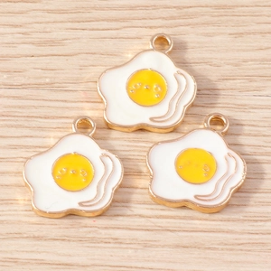 Detailed macro view of cute cartoon fried egg charms with golden edges for DIY jewelry