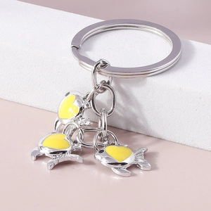 Détail du porte-clés poisson argenté avec des pendentifs en forme de cœur jaune poli