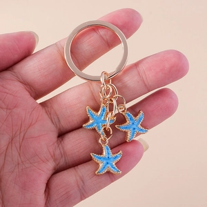 Détail des breloques étoile de mer bleues avec porte-clés doré tenu par la main
