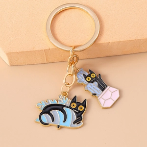 Detail of creative gold alloy keychain featuring black enamel cat and cactus pendants