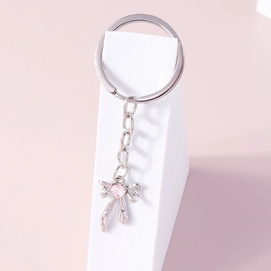 Creative silver bow keychain featuring a pink heart crystal pendant on a geometric stand
