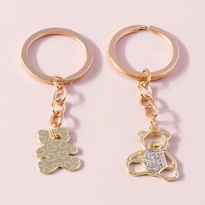 Close-up of golden bear keychains with hollow crystal pavé and heart pattern engraving