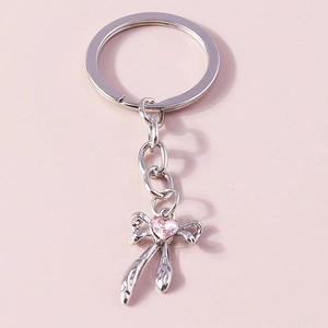 Detailed close-up of a silver bow keychain featuring a pink heart-shaped crystal stone