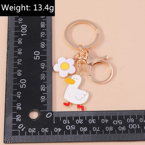 Close-up detail of cartoon duck keychain with white flower charm and golden metal clasp