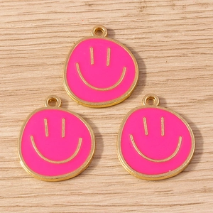 Detailed view of three pink enamel cartoon smiley face charms with gold alloy edges