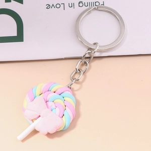 Detailed view of a rainbow lollipop keychain with a pink bow on a soft pastel background