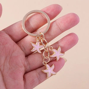 Détail d'un porte-clés doré orné de trois pendentifs en forme d'étoile de mer rose
