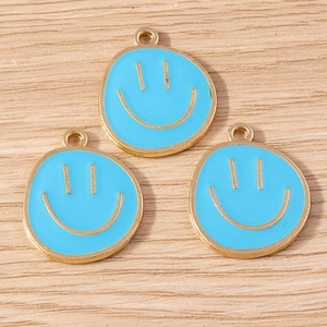 Macro shot of sky blue enamel smiley face charms with gold plating on wood