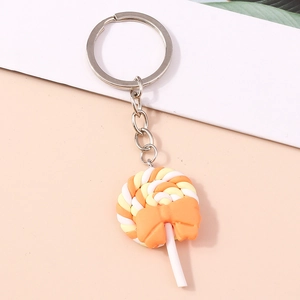 Detail of a resin lollipop keychain with orange bow and silver metal keyring