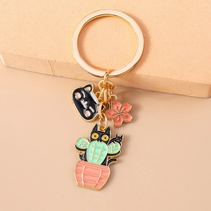 Detailed view of black cat cactus keychain with pink cherry blossom enamel pendant