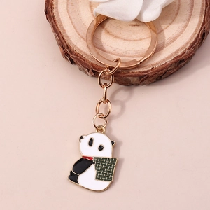 Vue détaillée d'un porte-clés panda en métal avec anneau doré sur un fond décoratif en bois