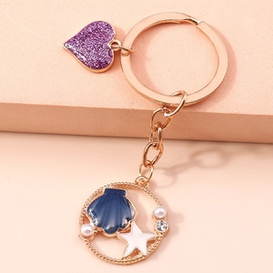 Dettaglio macro del portachiavi a tema marino con cuore glitter viola e conchiglia blu