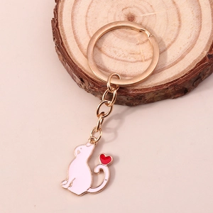 Détail du porte-clés chat émaillé rose avec petit cœur sur fond de bois naturel