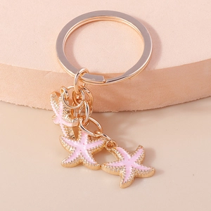 Porte-clés étoile de mer rose avec trois pendentifs dorés au style marin élégant