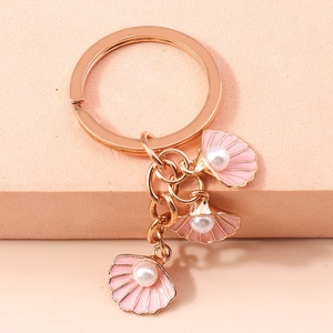 Dettaglio del portachiavi oro rosa con ciondoli a conchiglia in smalto rosa e perle