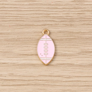 Macro shot of pink enamel American football charm with gold metal edges on wooden surface