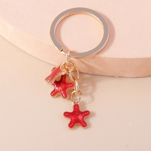 Porte-clés étoile de mer doré avec breloques rouges sur support de présentation
