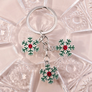 Détail du porte-clés flocon de neige argenté avec émail vert et strass rouge festif