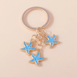 Détail des porte-clés étoile de mer dorés avec émail bleu clair et texture réaliste
