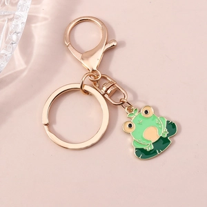 Détail d'un porte-clés en métal doré avec un charm de grenouille verte et un fermoir