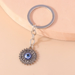 Détail du porte-clés soleil oeil maléfique argenté avec oeil bleu sur présentoir rose