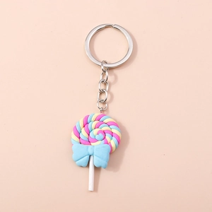Macro detail of a colorful spiral lollipop keychain with a blue bow on orange background