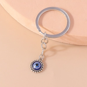Porte-clés œil bleu avec pendentif en verre et anneau argenté sur support rose doux